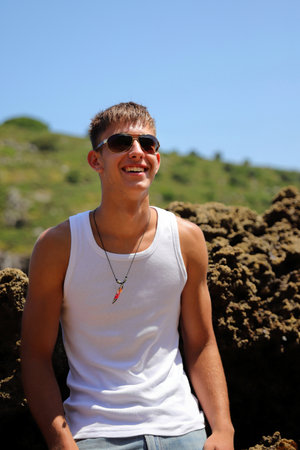 Young caucasian guy in sunglasses on the beach, casual teenager style, summer lifestyleの写真素材