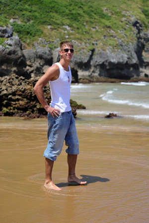 Young caucasian guy in sunglasses on the beach, casual teenager style, summer lifestyleの写真素材