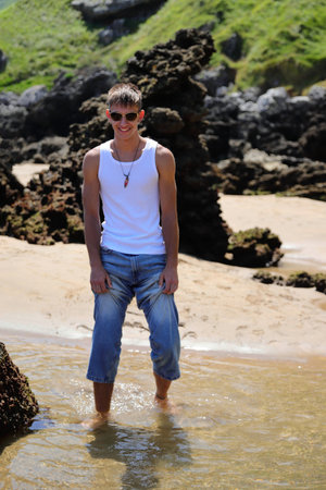 Young caucasian guy in sunglasses on the beach, casual teenager style, summer lifestyleの写真素材