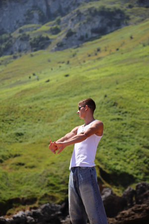 Young male in white sleeveless t-shirt and sunglasses on summer beach, tan skin, casual teenager lifestyle conceptの写真素材