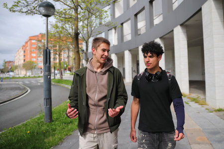 Two teenager boy walking on street, race diversity, students portraitsの写真素材