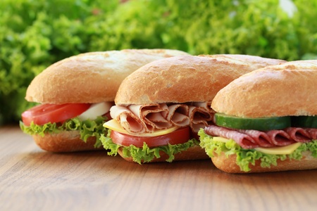 Closeup of three fresh sandwiches with turkey, salami and mozarellaの写真素材