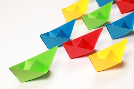 Green, red, yellow and blue paper boats on white backgroundの写真素材