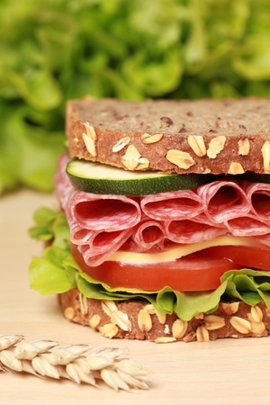 Fresh sandwich with salami, cheese and lettuce on a wooden tableの写真素材