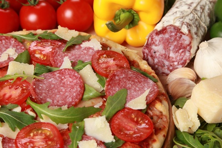 Pizza with salami, cheese, tomatoes and lettuceの写真素材