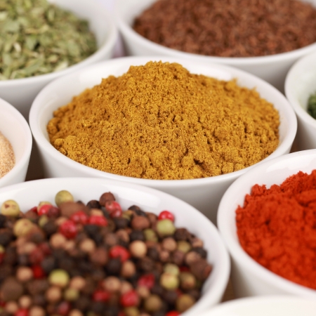 Various exotic spices in white bowls. Selective focus on the curry powder.の写真素材