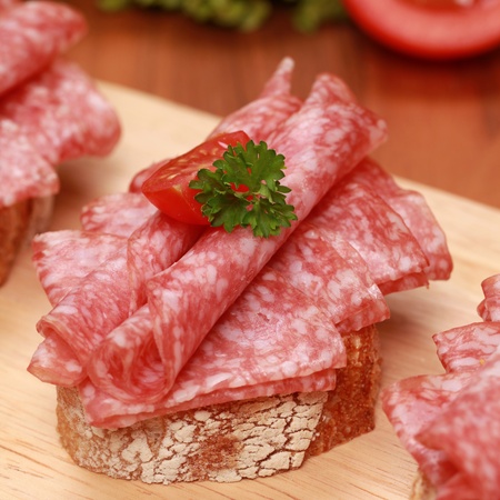 Fingerfood topped with fresh salami and small tomatoesの写真素材