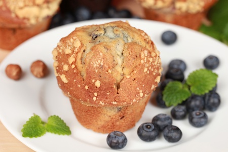 Blueberry muffin on a white plate served with hazelnutsの写真素材