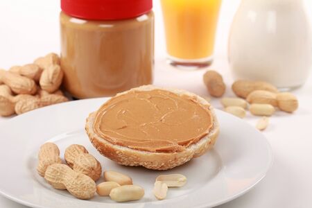 Delicious peanut butter on a bun with milk and a jar in the backgroundの写真素材