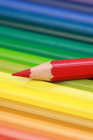 Red crayon on several colored crayons in a row with focus on the red crayon.の写真素材