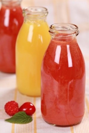 Freshly squeezed juice from red fruits and oranges in bottlesの写真素材