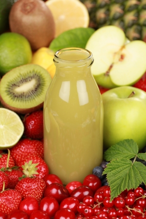 A bottle of kiwi and green apple smoothie surrounded by fresh fruitsの写真素材