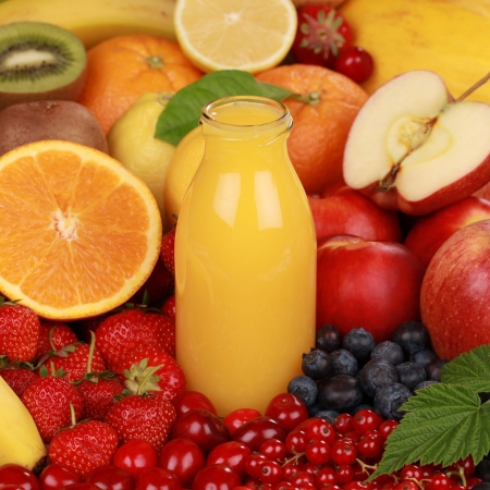 A bottle of orange smoothie surrounded by fresh fruits の写真素材