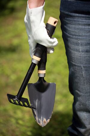 Garden hand trowel and hand fork in a womanの写真素材