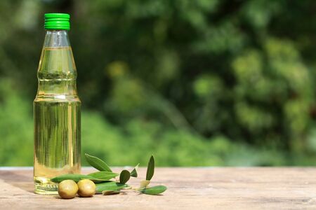 Olive oil in a small bottle on a wooden table with copyspace