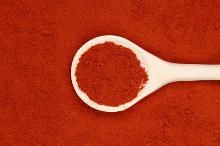 A wooden spoon lies on paprika powder forming a backgroundの写真素材