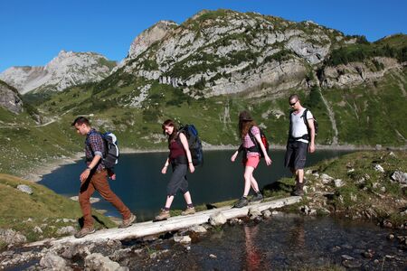 Young people cross a brook in the mountainsの写真素材