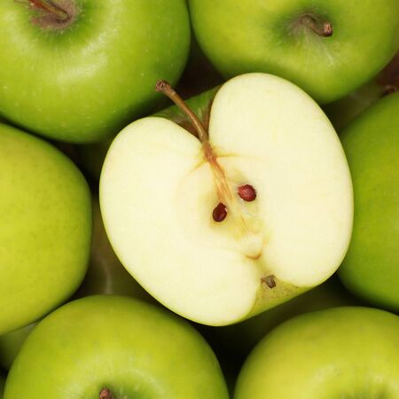 Group of green apples. One apple is sliced.の写真素材