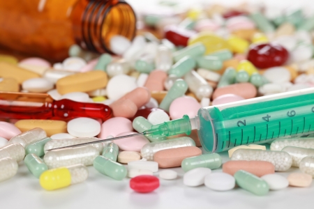 Variety of pills and capsules with a pill bottle and a syringeの写真素材