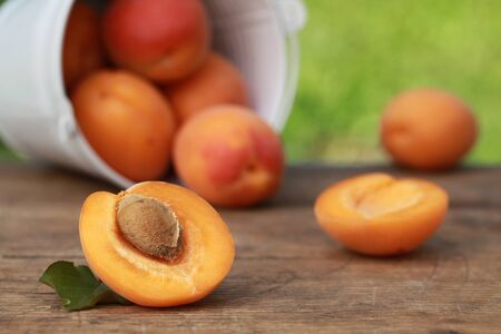 Apricots with leaves on a wooden table on light green backgroundの写真素材