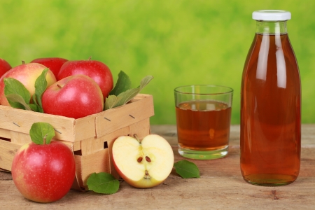 Fresh apple juice in a bottle and a glass next to ripe applesの写真素材