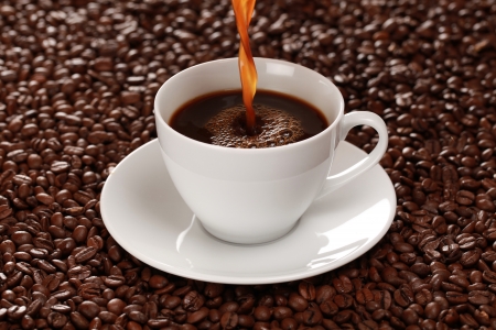 Hot coffee is pouring into a coffee cup. Selective focus.の写真素材