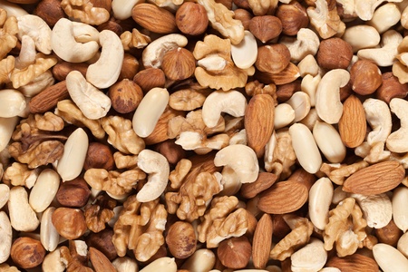 Collection of nuts such as peanuts, walnuts, almonds, hazelnuts, Brazil nuts and Macadamias forming a backgroundの写真素材