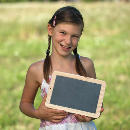 Portrait of a smiling girl holding a small blackboardの写真素材