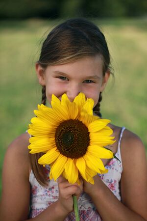 Happy young with a sunflower on a meadowの写真素材