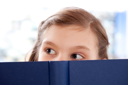 Little girl reading a book and looking upの写真素材