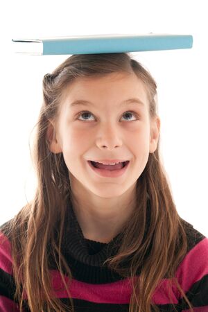 Young girl holding a book on her headの写真素材
