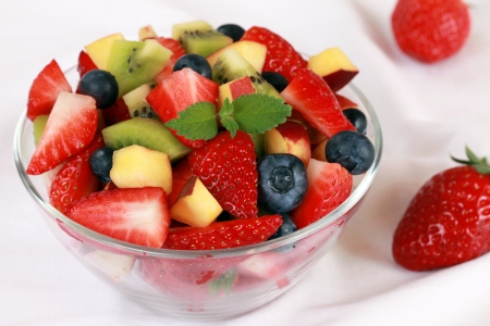 Fruit salad in a glass bowl with strawberries, blueberries and peachesの写真素材