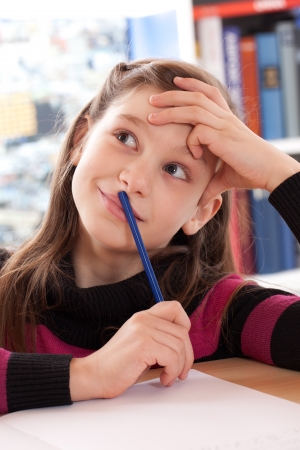 Little girl has a good idea while doing her homeworkの写真素材