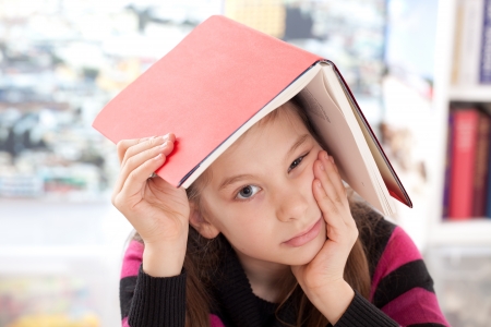 Girl with a book on her head as a symbol for overworkingの写真素材