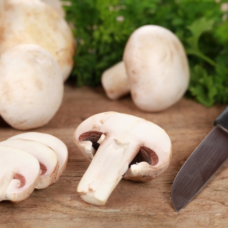 Food preparation: Sliced mushrooms with a knife on a chopping boardの写真素材