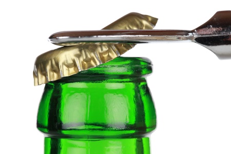 Opening a green beer bottle with an opener, isolated on white backgroundの写真素材