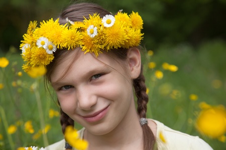 Little girl with flowers on her head on a meadow in natureの写真素材