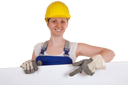 Young construction worker showing on a white sign, isolated on whiteの写真素材