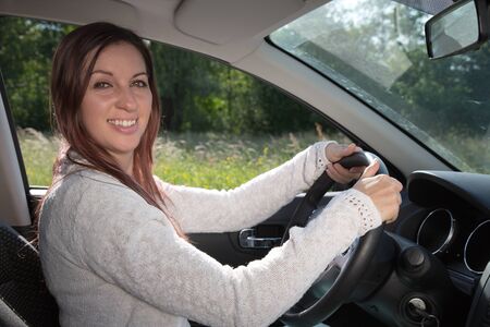 Happy woman driving a car and holding the steering wheel
