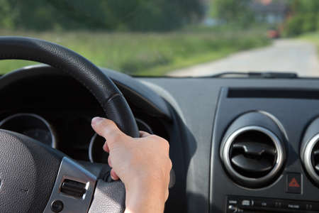 A young woman is holding the steering wheel while driving the car