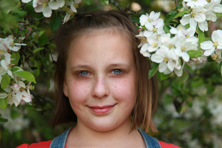 Smiling girl with freckles under a blooming apple tree in springの写真素材