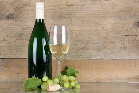 White wine in wine bottle and glass in front of a wooden backgroundの写真素材