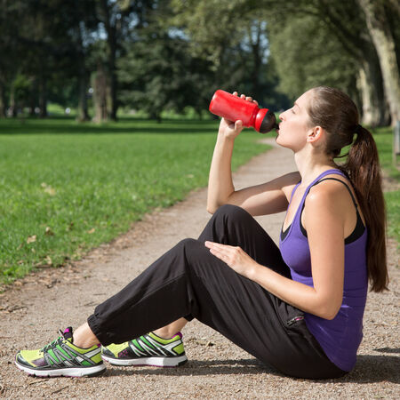 Young woman takes a break for drinking during sports or runningの写真素材