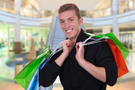 Smiling young man shopping or buying in a store or mallの写真素材