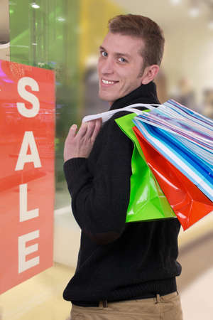 A smiling man with shopping bags in a clothing storeの写真素材