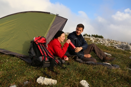 Young people are drinking water while camping in the mountainsの写真素材