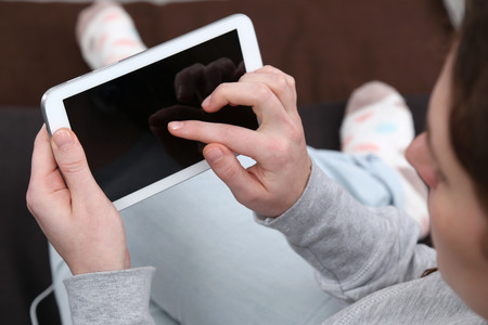 A young woman is using her tablet computer with a finger