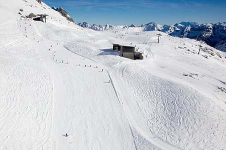 Snow covered ski slope with skiers in the mountains Alpsの写真素材