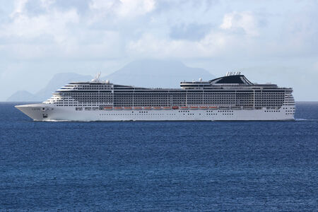 A cruise ship is sailing in the sea in front of a tropical islandの写真素材