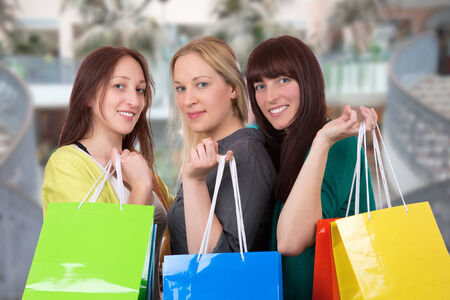 Group of smiling young women with shopping bags having fun while shopping in a shopping mallの写真素材